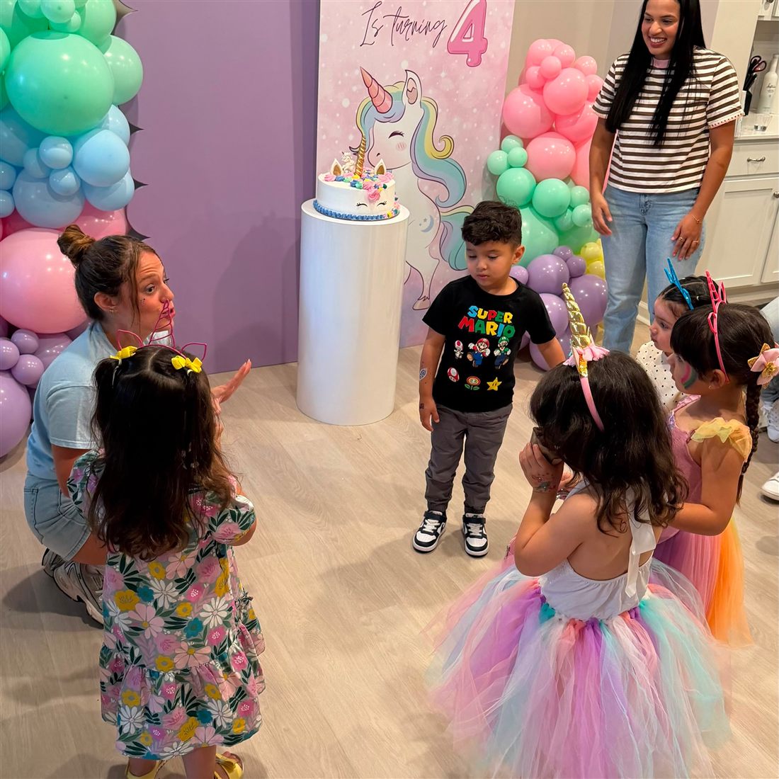 Children playing a game in front of a unicorn balloon backdrop